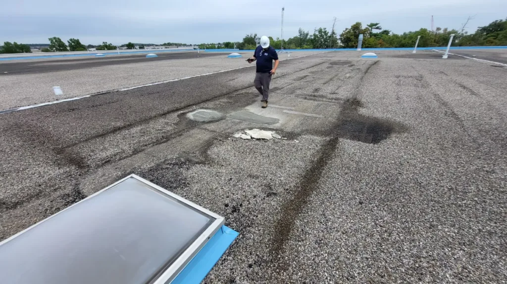 Technician inspecting a skylight and membrane on a flat roof